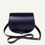 Navy leather saddle bag with a strap on a white background