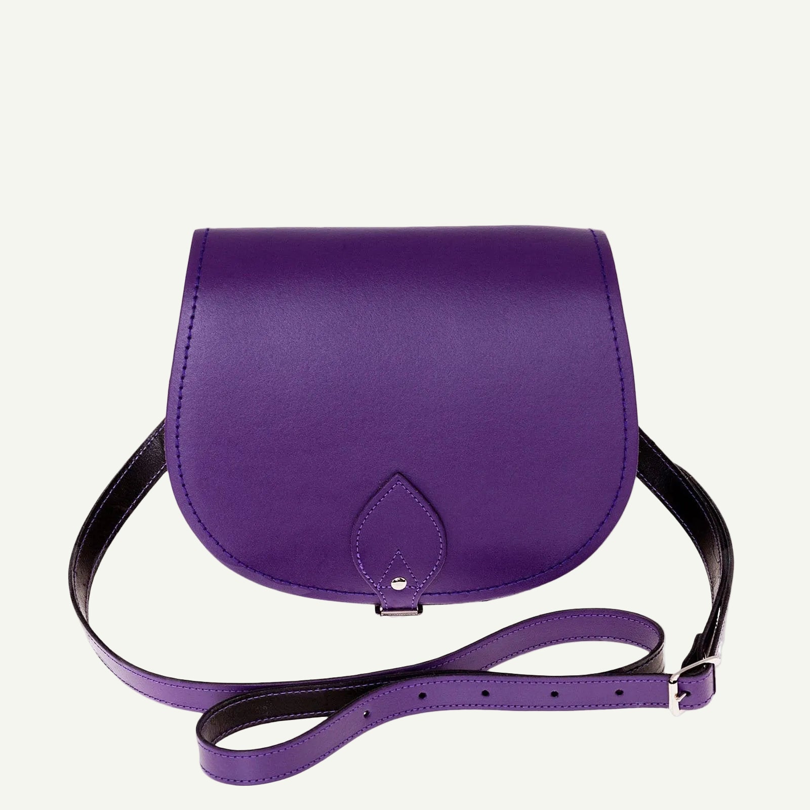 Purple leather handbag with a black strap on a white background