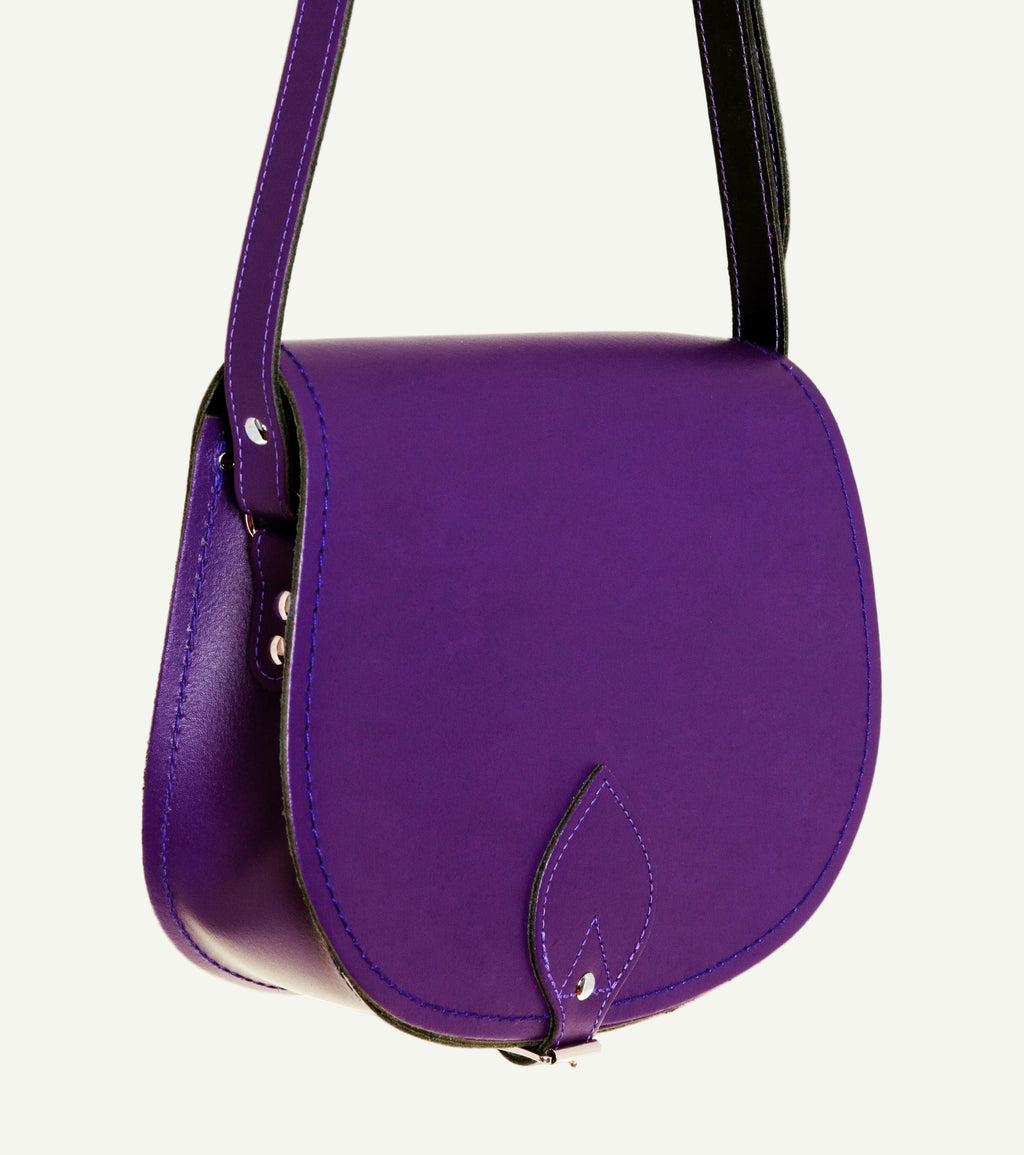 Purple handbag with a black strap on a white background