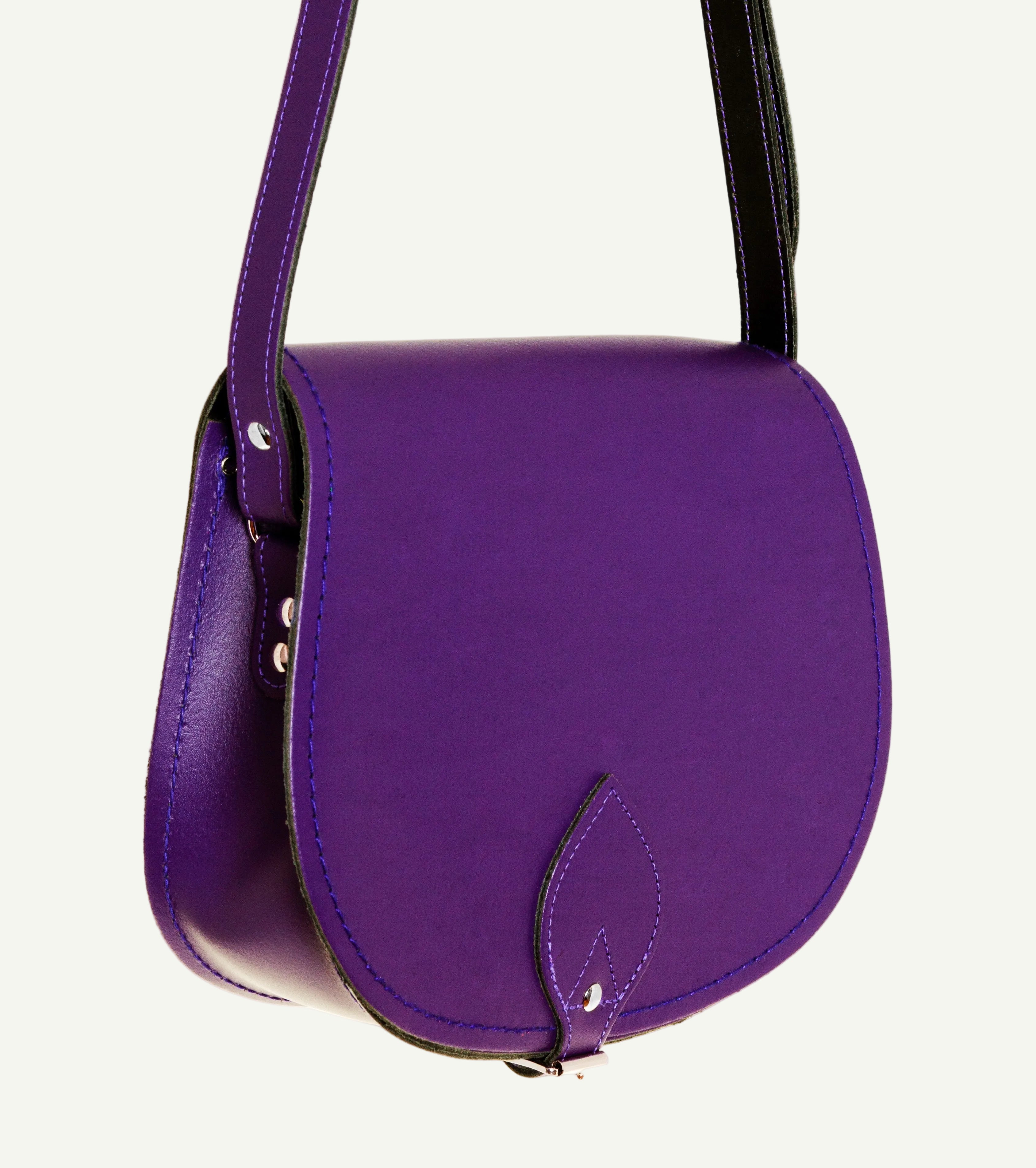 Purple handbag with a black strap on a white background
