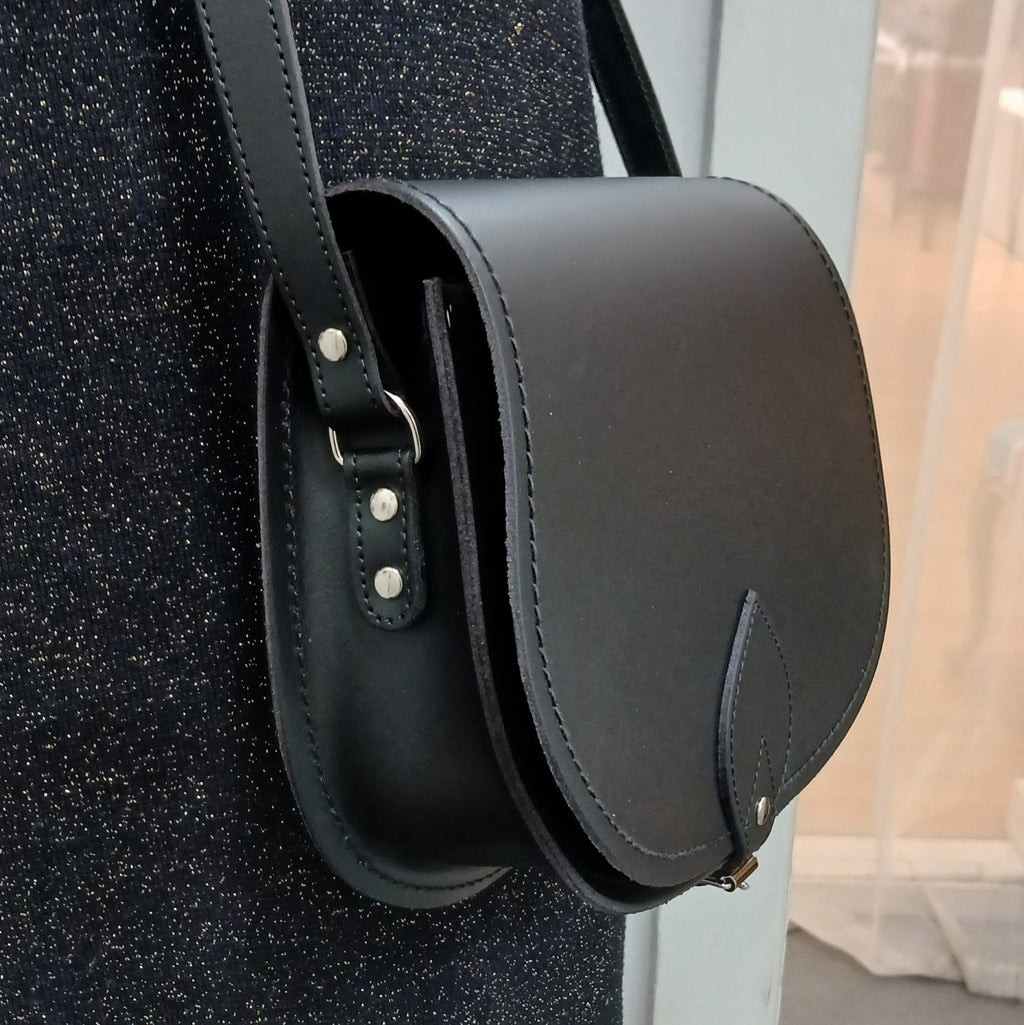 Black leather handbag with a strap on a textured surface