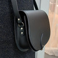 Black leather handbag with a strap on a textured surface