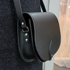 Black leather handbag with a strap on a textured surface